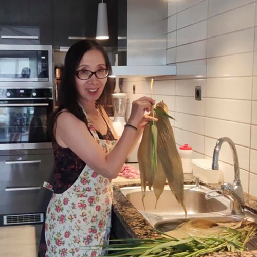 Kvinna i kök, håller upp grönsaker 